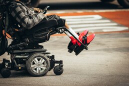 An individual is shown using an electric wheelchair in an urban environment